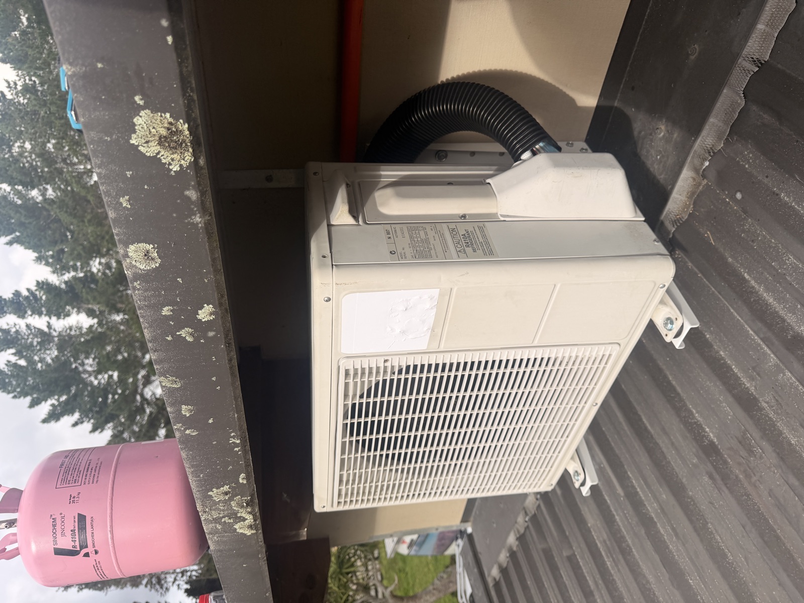 Outdoor heat pump unit mounted on levelled brackets under the eave of a roof, drain and line set insulated